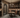 Wine cellar with wooden table and chairs, stone archway, and wine racks.