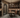 Wine cellar with wooden table and chairs, stone archway, and wine racks.
