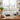 Wine bottles on a rack in a kitchen setting with a window and sink in the background.
