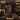 Wine cellar with shelves filled with bottles in a dimly lit room with chandeliers and a fireplace.